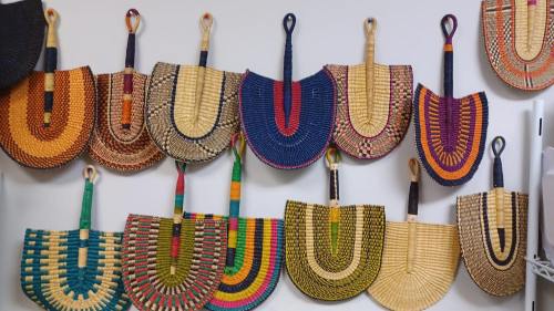 A collection of colorful woven baskets displayed on a wall, featuring various patterns and shapes.