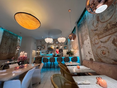 A stylish restaurant interior featuring elegant lighting, decorative walls, and a cozy dining area with modern furnishings.