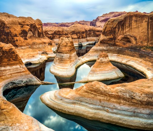 A serene landscape featuring unique rock formations and calm water reflecting the sky in a canyon setting.