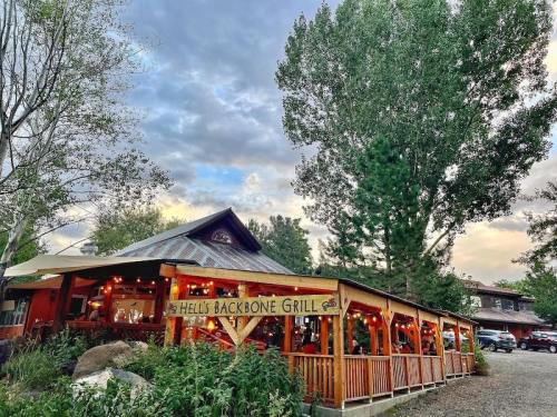 A rustic restaurant with a wooden patio, surrounded by trees and a cloudy sky, inviting diners to enjoy the outdoor space.