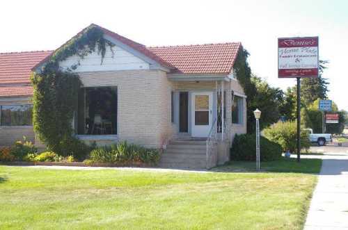 A brick building with a red roof and ivy, featuring a sign for Denise's Family Restaurant and a grassy area in front.