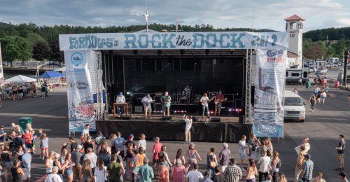 A lively outdoor concert scene with a band performing on stage and a crowd enjoying the music at a festival.