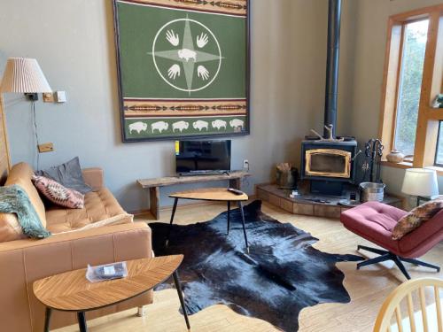 Cozy living room with a leather sofa, wooden tables, a fireplace, and a decorative wall hanging featuring hands and bison.