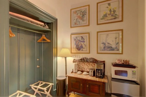 A cozy corner with a closet, framed art, a lamp, a coffee maker, and a microwave in a well-decorated room.