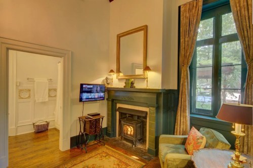Cozy living space with a fireplace, TV, and large windows, featuring elegant decor and warm lighting.