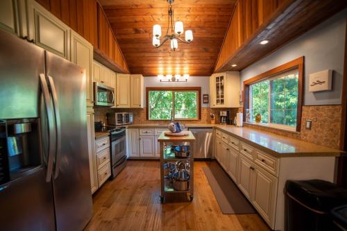 Bright kitchen with wooden beams, stainless steel appliances, and a central island, surrounded by large windows.