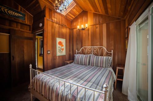 Cozy wooden bedroom featuring a striped bed, warm lighting, and rustic decor.