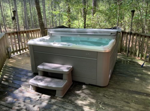 A hot tub on a wooden deck surrounded by trees in a serene outdoor setting.