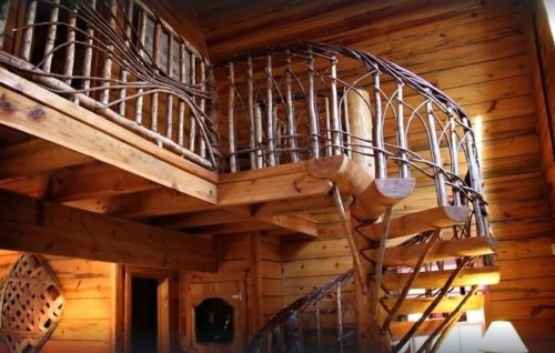 A rustic wooden interior featuring a spiral staircase with a decorative railing and warm, natural lighting.