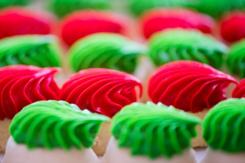 Colorful cookies topped with red and green swirled frosting, arranged in a neat pattern.