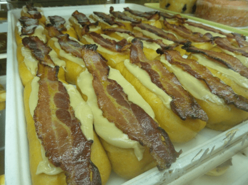 A tray of golden pastries topped with creamy filling and crispy bacon strips.