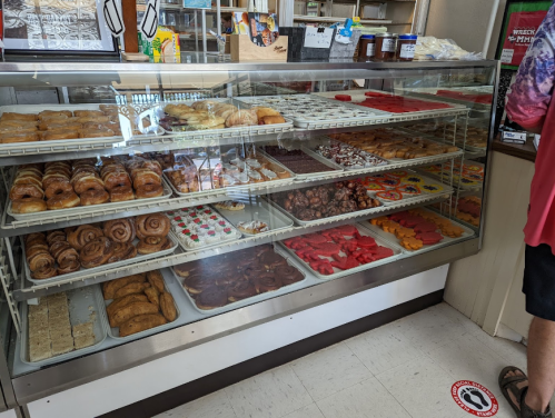 A display case filled with various baked goods, including pastries, donuts, and cookies, in a bakery setting.