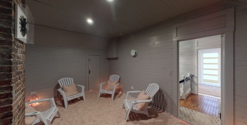Cozy room with four white chairs, soft lighting, and a doorway leading to another space. Warm, inviting atmosphere.