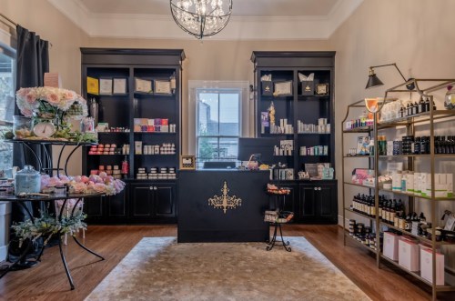 A cozy boutique interior with shelves of beauty products, a central display counter, and elegant decor.