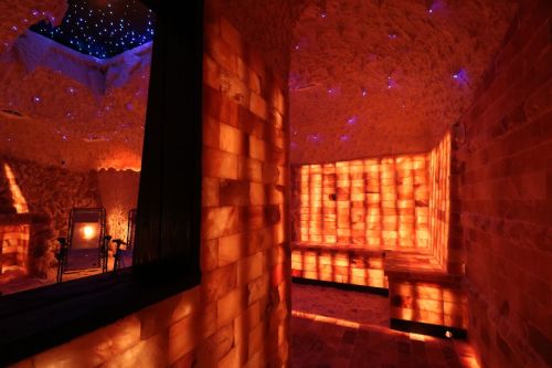 A serene salt room with glowing orange salt walls and a starry ceiling, creating a calming atmosphere.