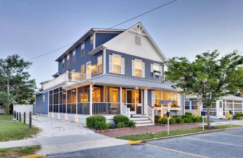 A charming blue and white house with a porch, surrounded by greenery and a clear evening sky.