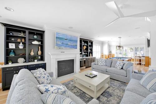 Bright living room with light blue sofas, a coffee table, and a fireplace, featuring nautical decor and large windows.