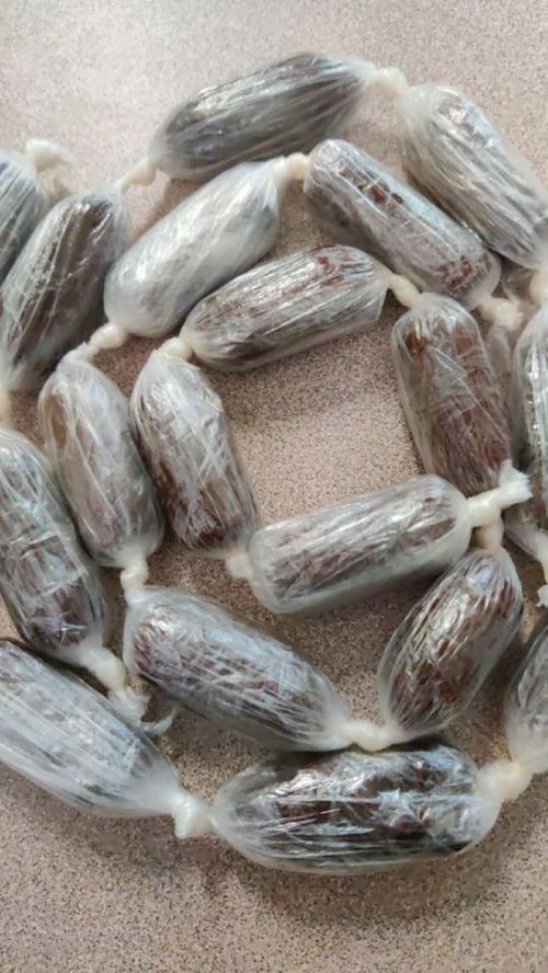 A close-up of a string of wrapped, oval-shaped objects, resembling dates, arranged in a circular pattern.