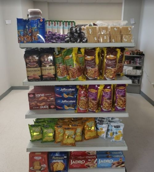 A display shelf filled with various snacks, including cookies, crackers, and chips, in a store setting.