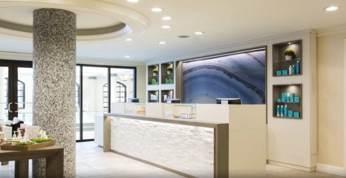 Modern reception area with a stone counter, decorative shelves, and a large abstract wall art piece. Bright and inviting space.