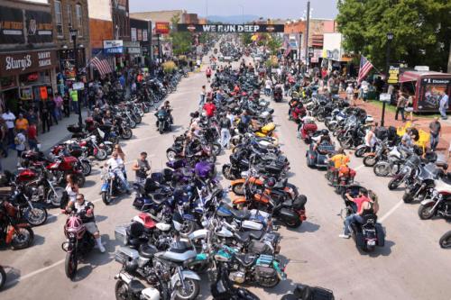 A bustling street filled with numerous motorcycles and crowds of people enjoying a vibrant outdoor event.