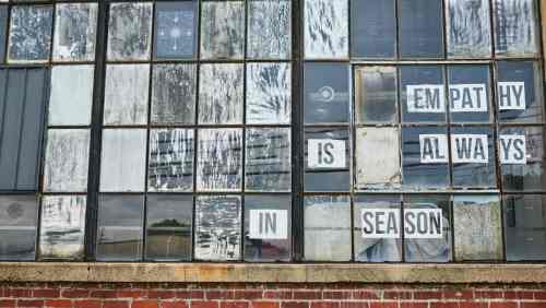 A weathered window with a message reading "Empathy is always in season" displayed on the panes.