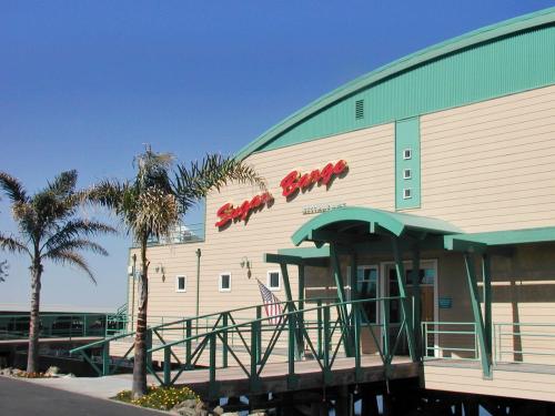 Exterior of a building named "Super Burgers," featuring palm trees and a ramp leading to the entrance. Clear blue sky.