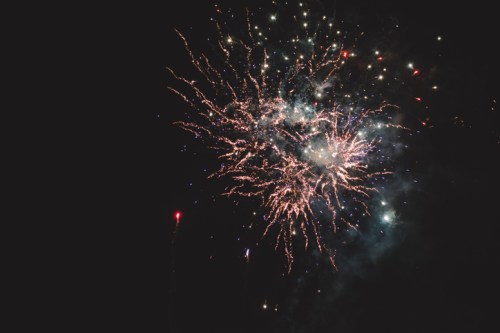 Colorful fireworks burst in the night sky, creating a dazzling display of light and sparks against a dark background.