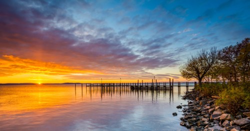 The sun sets over the water near Havre de Grace, Maryland, with a pier in the distance