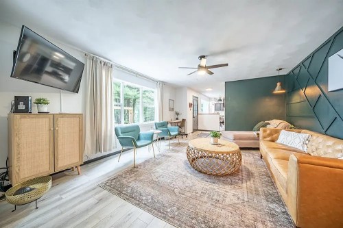 Cozy living room with a mix of modern and vintage decor, featuring a large window, comfortable seating, and a stylish rug.