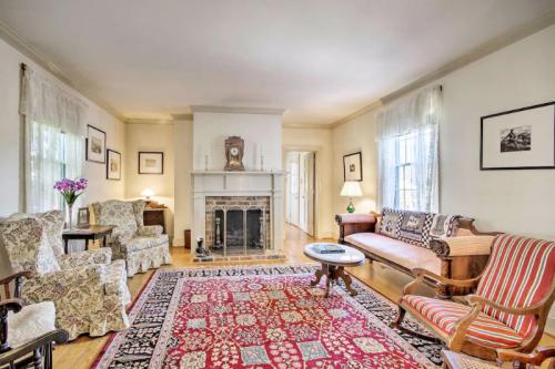 Cozy living room with floral armchairs, a wooden sofa, a fireplace, and a patterned rug. Natural light from windows.