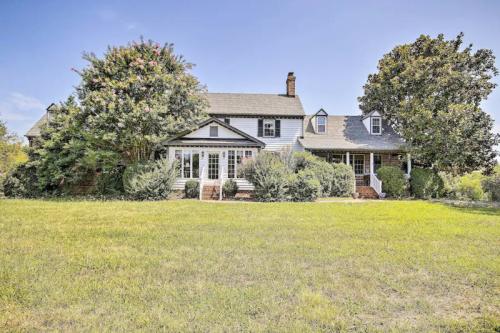 A large, two-story house with a front porch, surrounded by greenery and a spacious lawn under a clear blue sky.