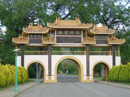 Entrance gate to the City of Ten Thousand Buddhas, featuring ornate architecture and lush greenery.