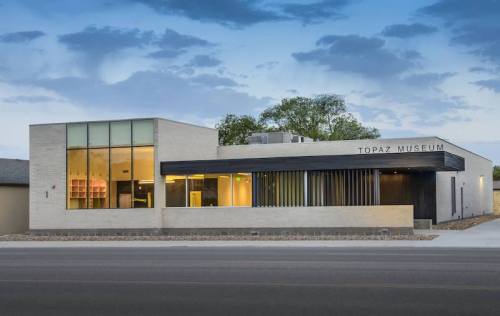 Modern building of the Topaz Museum, featuring large windows and a sleek design against a cloudy sky.