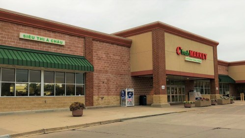 Exterior of a grocery store with a green awning, featuring signs for "Fresh Market" and "Siêu Thị A Châu."