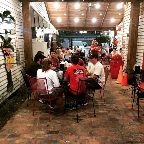 A group of people dining at an outdoor restaurant with string lights and a cozy atmosphere.