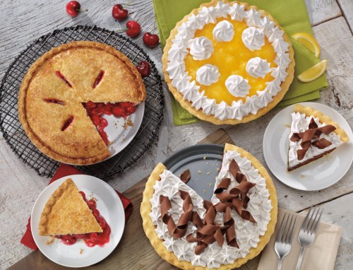 A variety of pies on plates: cherry pie, lemon meringue pie, and chocolate cream pie, with slices cut and served.