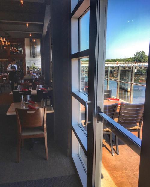 A view from inside a restaurant, showcasing tables and a large window overlooking a scenic outdoor area.