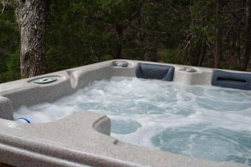 A hot tub with bubbling water, surrounded by trees in a natural setting.
