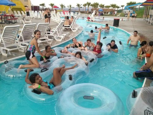 A group of people enjoying a lazy river at a water park, floating on inner tubes and having fun in the sun.