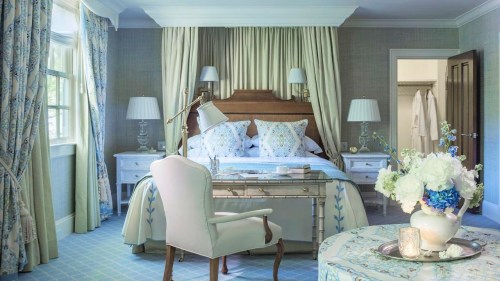 A beautifully decorated bedroom with floral accents, a desk, and soft lighting, creating a serene atmosphere.