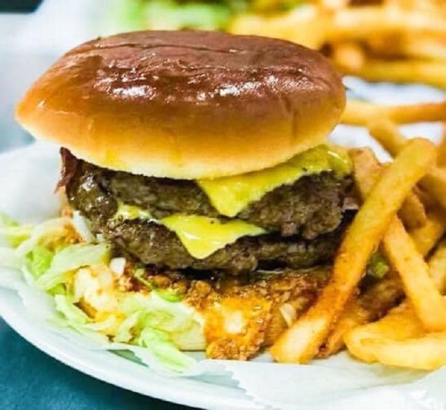 A juicy double cheeseburger with melted cheese on a bun, served with crispy French fries and lettuce.