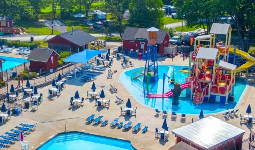 Aerial view of a vibrant water park with pools, slides, and lounge chairs surrounded by greenery.