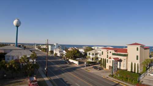 A coastal view featuring a water tower, buildings, and the ocean under a clear blue sky.