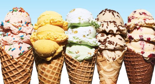 Five ice cream cones with various flavors, including pink, yellow, green, and brown, topped with sprinkles and chocolate.