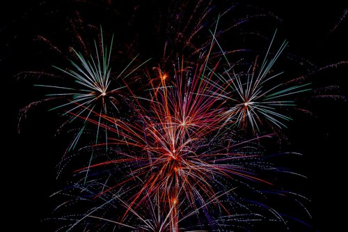 Colorful fireworks burst against a dark night sky, creating vibrant trails of light in various colors.