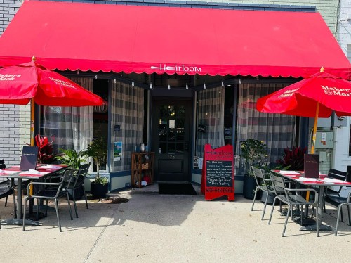 A restaurant entrance with a red awning, outdoor seating, and a chalkboard menu outside.