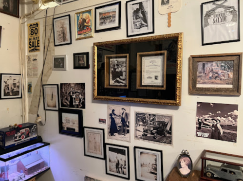 A wall adorned with various vintage photographs, framed certificates, and memorabilia in a cozy setting.
