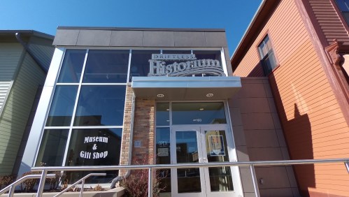 Exterior of the Driftless Historium, a museum and gift shop, featuring large windows and a modern entrance.