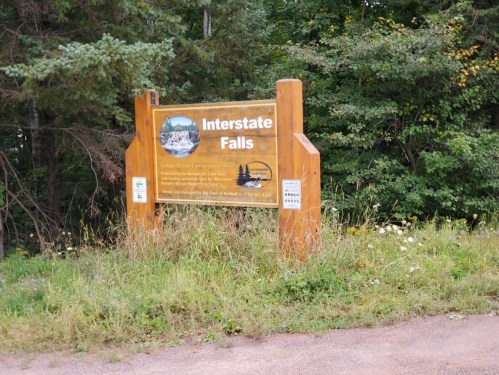 Sign for Interstate Falls surrounded by greenery, indicating the location and features of the area.